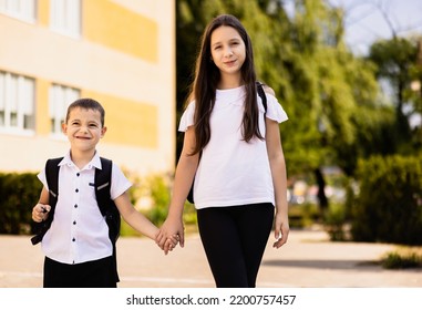 The Older Sister Takes Care Of The Younger Brother, Holds His Hand And They Go To School.