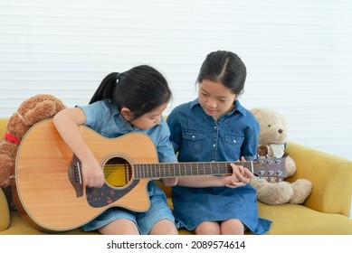 older sister teach her younger sibling to play guitar at home