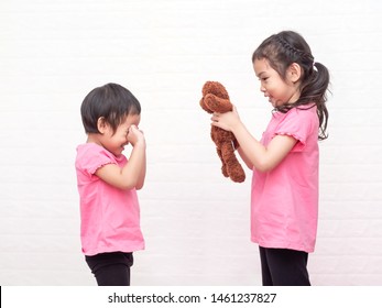 The older sister tried to comfort her younger crying and giving a teddy bear. The older sister take care to her younger sister.