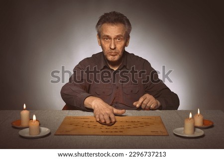 Older spiritist communicating with ghosts through ouija