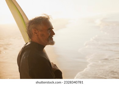 Older surfer carrying board on beach - Powered by Shutterstock