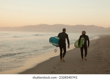 Older surfers carrying boards on beach - Powered by Shutterstock