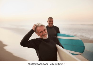 Older surfers carrying boards on beach - Powered by Shutterstock