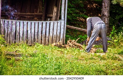 Older white haired man gathering firewood from forest to feed fire for outdoor smoking food in wooden shed  in rural Georgia - Powered by Shutterstock