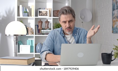 Older White Man Sitting At Desk Using Laptop In Home Office. 50s Businessman On Video Chat Conference Call And Working From Home.