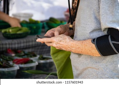 Older Woman With Arm Brace And Cell Phone At Farmers Market - Close-up And Selective Focus