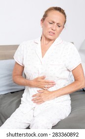 Older Woman In Bed With Stomach Pain