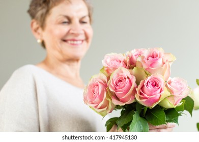 Older Woman In Beige Top Holding Pink Rose Bouquet (selective Focus)