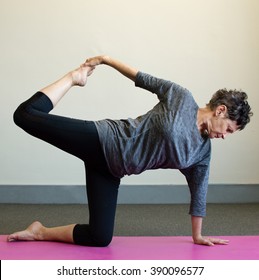 Older Woman In Black And Grey Clothing In Yoga Position On Pink Mat