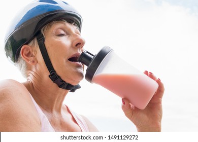 Older Woman With Blue Helmet Drinking Protein Shake