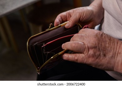 The Older Woman Counts The Money. An Elderly Woman Caucasian Old Woman Gray-haired Grandmother Takes Money Out Of Her Purse And Counts It. Old Hands Hold Bills. 