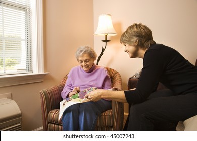 Older Woman Does Needlepoint While Another Woman Watches. Horizontal Shot.