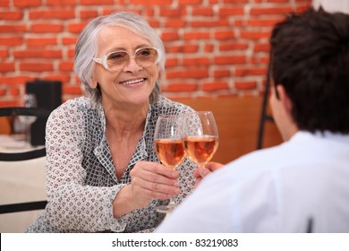 Older Woman Drinking Rose Wine In A Restaurant With A Young Man