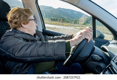 Older Woman Driving A Car, On A Sunny Day.