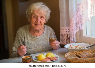 Older woman eating at home at the table.