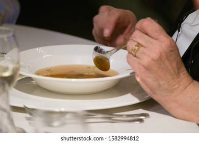  Older Woman Eating Soup At A Restaurant Setting