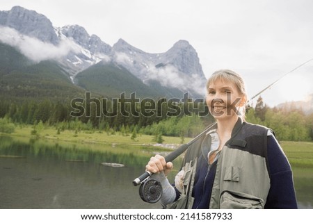 Older woman fishing in still lake