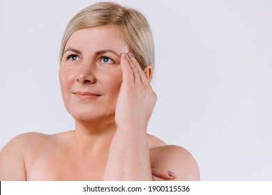 The Older Woman Frowns Upward And Is Unhappy With The Wrinkles On Her Face. White Background. Enlarged Portrait. Anti-aging, Spa And Beauty.