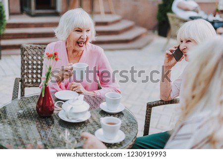 Older woman having fun with her friends. Females sitting at the table outdoor