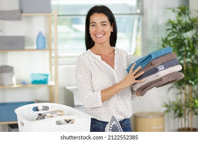 Older Woman Holding Pile Of Ironed Laundry