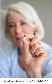 Older woman holding a pill