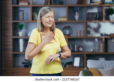 Older Woman At Home Doing Fitness Has Severe Shortness Of Breath And Chest Pain, Compares Bullets On Fitness Bracelets