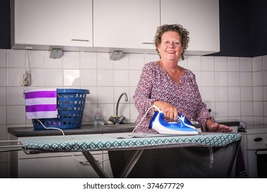 Older woman Ironing clothes. Happy older woman ironing clothes. - Powered by Shutterstock