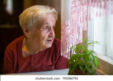 Older Woman With Longing Looks Out The Window.