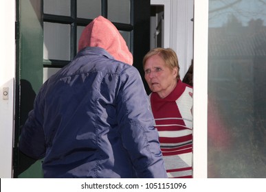 Older Woman Looks Scared At A Suspicious Person At The Door