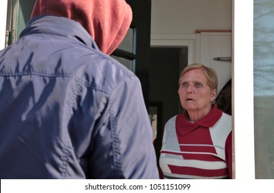 Older Woman Looks Scared At A Suspicious Person At The Door