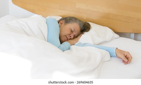 Older Woman Lying In Bed And Sleeping Peacefully