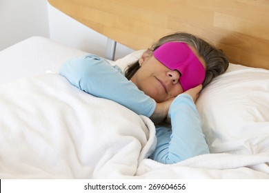 Older Woman Lying In Bed And Sleeping Peacefully With A Sleep Mask On