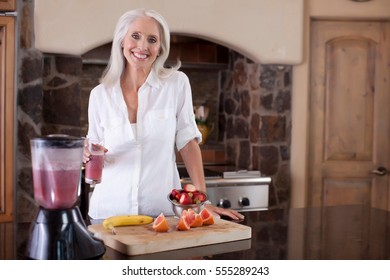 Older Woman Making Smoothie In Kitchen