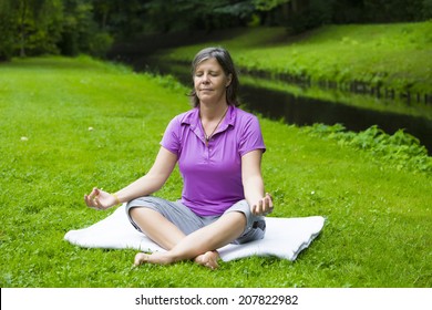 Older Woman In Park By A River Doing Yoga