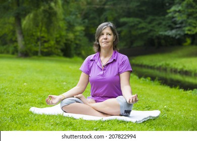 Older Woman In Park By A River Doing Yoga