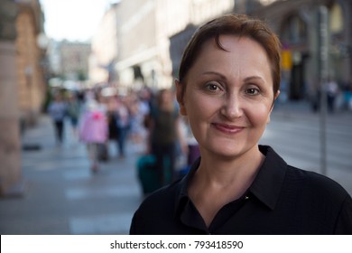 Older woman portrait. Professional headshot of middle aged 40 50 years old woman outdoors. City street shot.