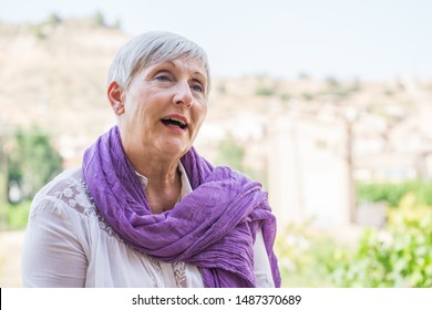 Older Woman With Purple Scarf On Her Neck And White Hair Smiling