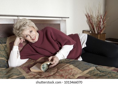 Older Woman Reading Book On Bed