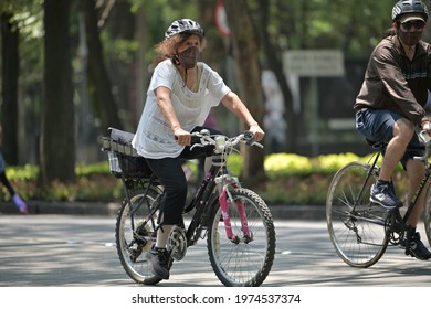 Older Woman Riding A Bicycle In The Streets And Wearing A Protective Mask. Mexico, Mexico City, May 16, 2021.