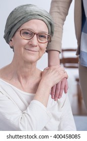 Older Woman With Scarf With Cancer And Her Daughter Holding Hand On Mother's Shoulder