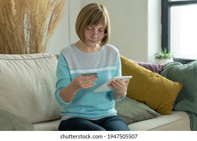 Older Woman Shopping Online With Credit Card Using Digital Tablet. Modern Retired Woman Holding Bank Card While Shopping Online Via Tablet 