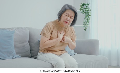 An Older Woman With Short Hair Was Sitting On The Sofa And Was Suffering From Painful Chest Pain From A Chronic Disease