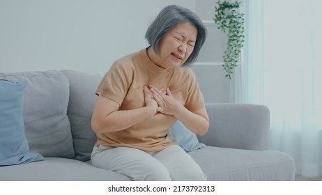 An Older Woman With Short Hair Was Sitting On The Sofa And Was Suffering From Painful Chest Pain From A Chronic Disease.