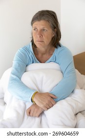 Older Woman Sitting In Bed And Looking Sad