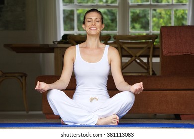 Older Woman Sitting On Floor In Yoga Position At Home