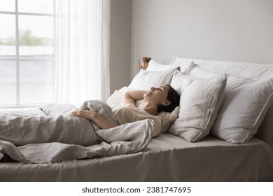 Older woman sleeping alone in double bed in modern, light bedroom, looks serene while resting in early morning at home, enjoy comfortable orthopaedic mattress and fresh beddings, having healthy sleep - Powered by Shutterstock