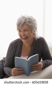 Older Woman Smiling While Reading A Book.