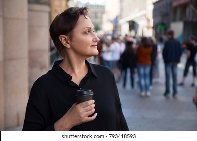 Older Woman Street Portrait. Middle Aged Woman Walking In City. Outdoor Head Shot Of 45 50 Year Old Relaxed Woman On Lunch Break Drinking Coffee. Urban Background. Street Style