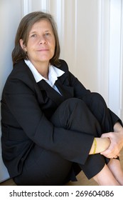 Older Woman In A Suit Sitting In A Corner