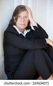 Older Woman In A Suit Sitting Depressed In A Corner